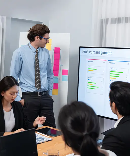 Diverse team of professionals managing projects using an IT management system in a modern office environment, highlighting collaboration and digital workflow.