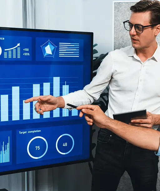 Business professionals analyzing CRM dashboard during office meeting, showcasing customer data insights, sales performance, and client relationship metrics on a large screen.