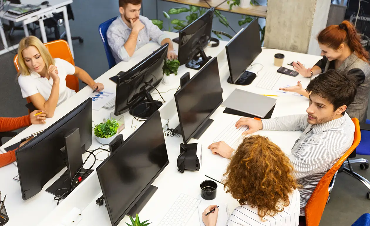 Group of young business professionals collaborating in a modern coworking office, reflecting dynamic team culture and collaborative working environment in an IT company.