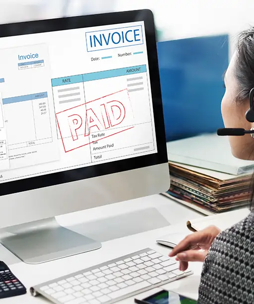 Invoice marked as paid on a desk with calculator and documents, representing digitized paperwork and financial processing through an IT management system.